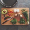 Une planche à découper, un couteau un demi avocat, des champignons de Paris et diverses herbes aromatiques